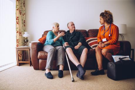 Caregiver and patient talking with support person on the sofa in their living room