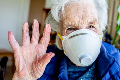 closeup of older woman wearing mask waving