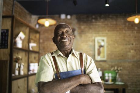 Portrait of smiling older man looking at camera in his shop