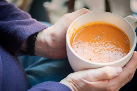 Images of an older adult's hands holding a bowl of soup