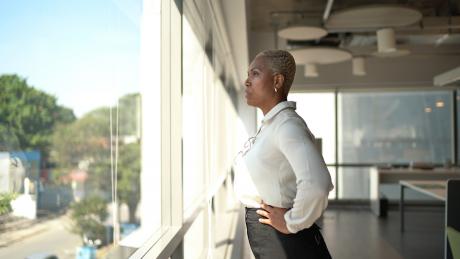 Business woman looks out window, contemplative