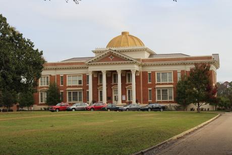 Large red brick building with white columns and a gold dome.