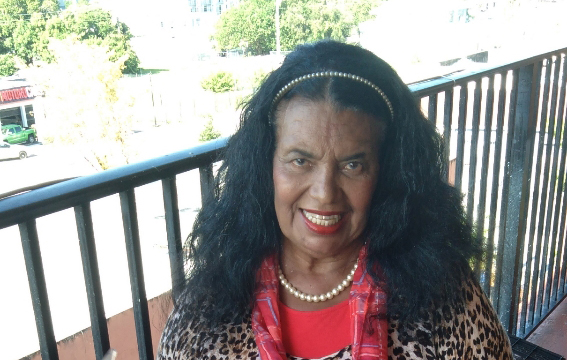 Juanita Alvarez wearing a leopard print shirt and red scarf smiling at the camera