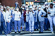 Photo of medical workers wearing protective gear in front of a healthcare facility