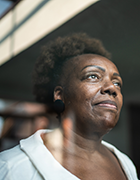 Photo on older Black woman looking out of a room