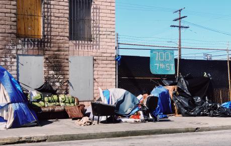 Photograph of tents and a couch on a sidewalk
