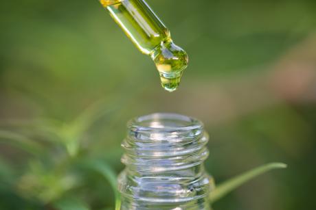 Dropper over a small glass bottle. Dropping in a drop of hemp oil.