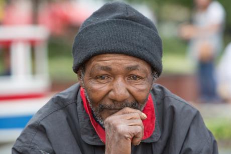 Portrait of homeless man thinking while sitting outdoors during the daytime