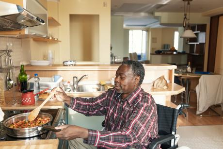 older Black man in wheelchair making lunch on his stovetop at home