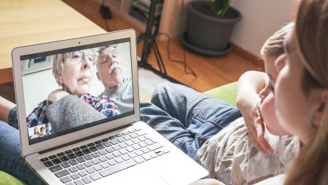 a mother and young child on a video call with grandparents