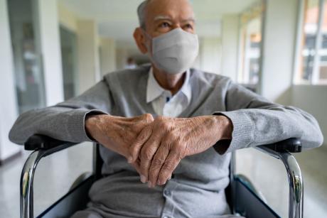 Older adult in a wheelchair at the hospital wearing a facemask 