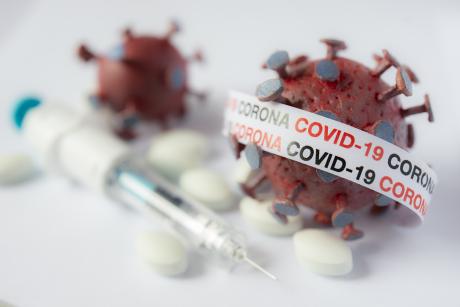 an image of a syringe next to a model of the COVID19 virus