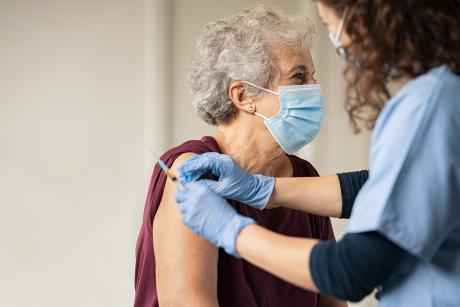 older woman wearing a mask while getting a shot