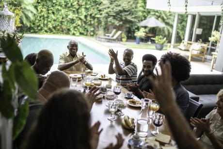 Black family at large table, everyone is happy, talking, smiling