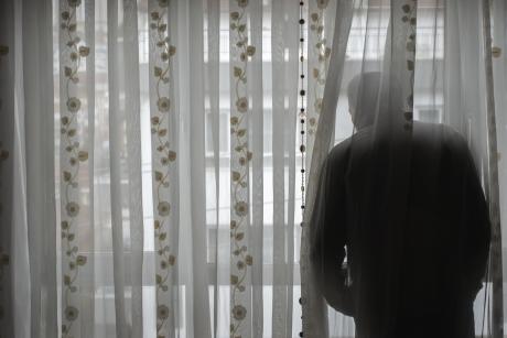 Man alone, looking out window in dark room