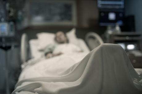 blurred image of an older person along in hospital, lying in bed