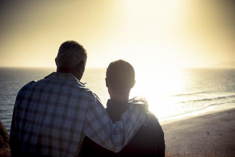 older gay couple looking over the beach.