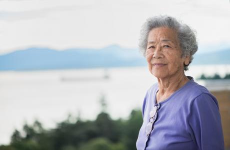 Older Asian woman smiling, looking confidently at camera