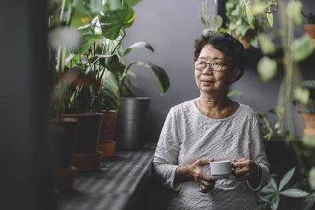 An older Asian woman standing in a room full of plants