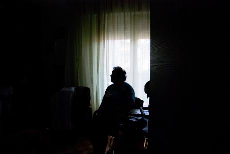 Older woman sitting alone in dark room