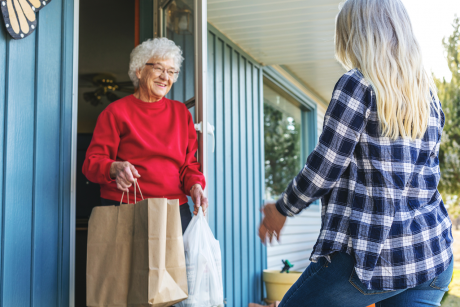 Photo of older woman receiving grocery delivery at home