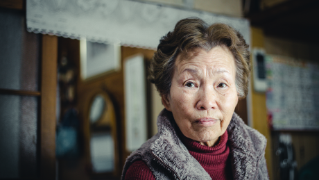 an older Asian woman in her home looking at the camera