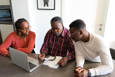 An older Black man with his two grown children looking over finances