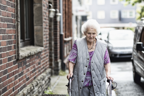 Older white woman walking on a sidewalk.