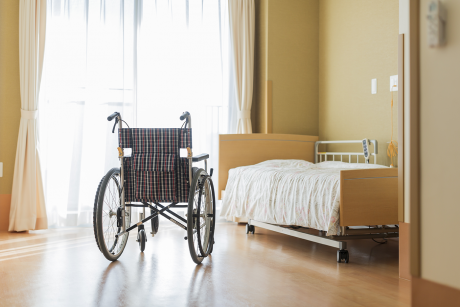 Empty wheelchair next to empty bed in nursing home