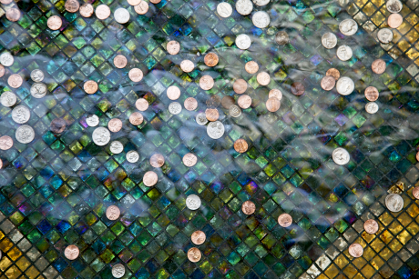 Photo of coins sitting in the pool of a public fountain