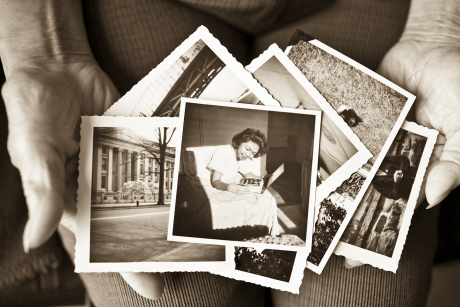 Woman displays old photos in her hands.