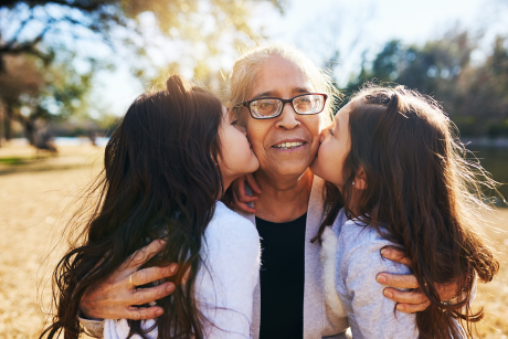 Smiling Latina grandmother hugs grandkids