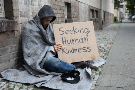 Homeless man holds sign Seeking Human Kindness