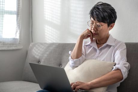 Slightly depressed woman on laptop on couch