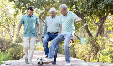 Three adult men play soccer