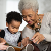 Grandmother reads with grandson, mother helps