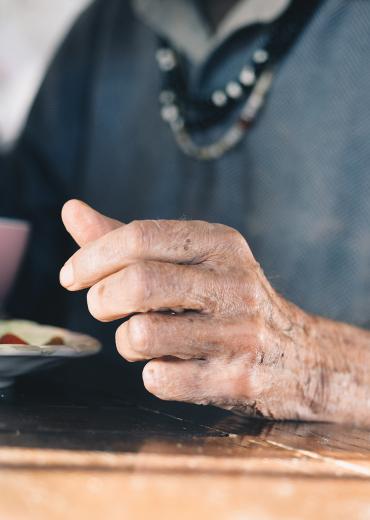 closeup of an older man's hand next to his plate of food