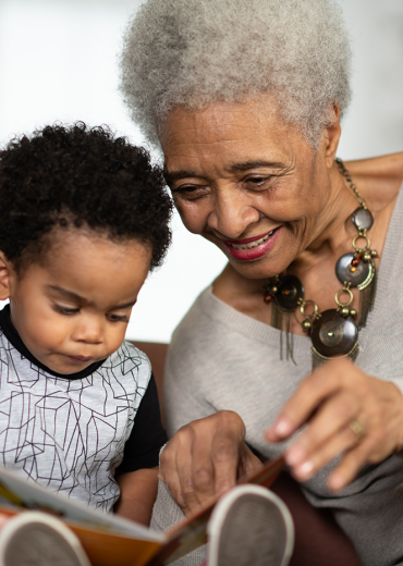 Grandmother reads with grandson, mother helps