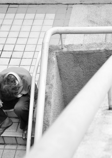 Homeless man looking down stairs, illustrating over the edge