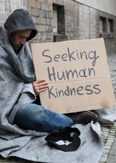 Homeless man holds sign Seeking Human Kindness