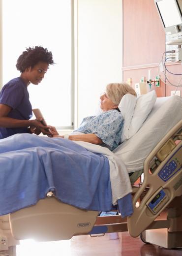 Nurse showing older adult tablet in hospital