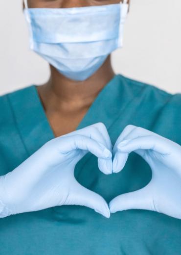 Nurse in mask makes heart sign