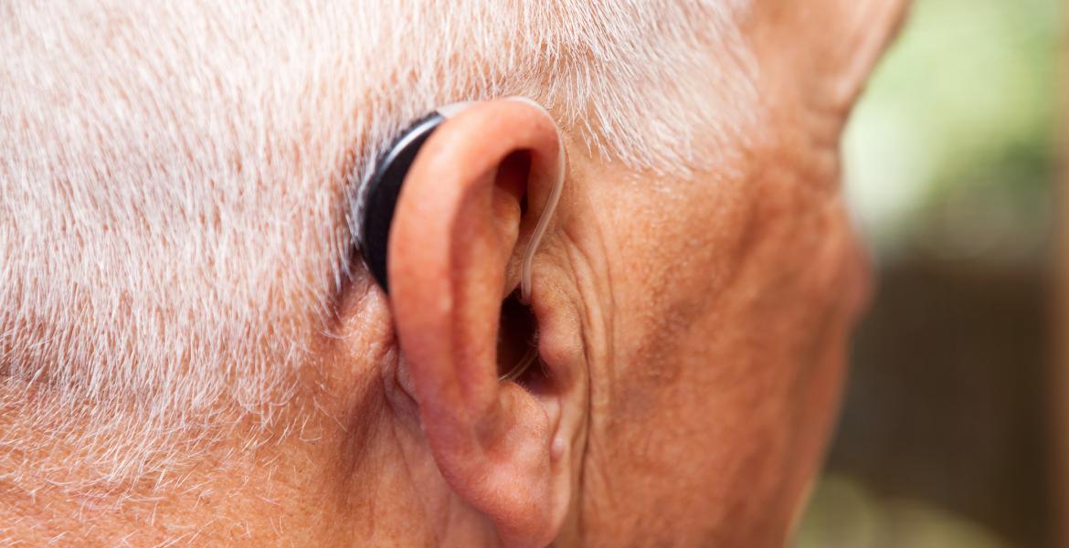 Older man's ear with with a very modern, low-profile and discrete hearing aid.