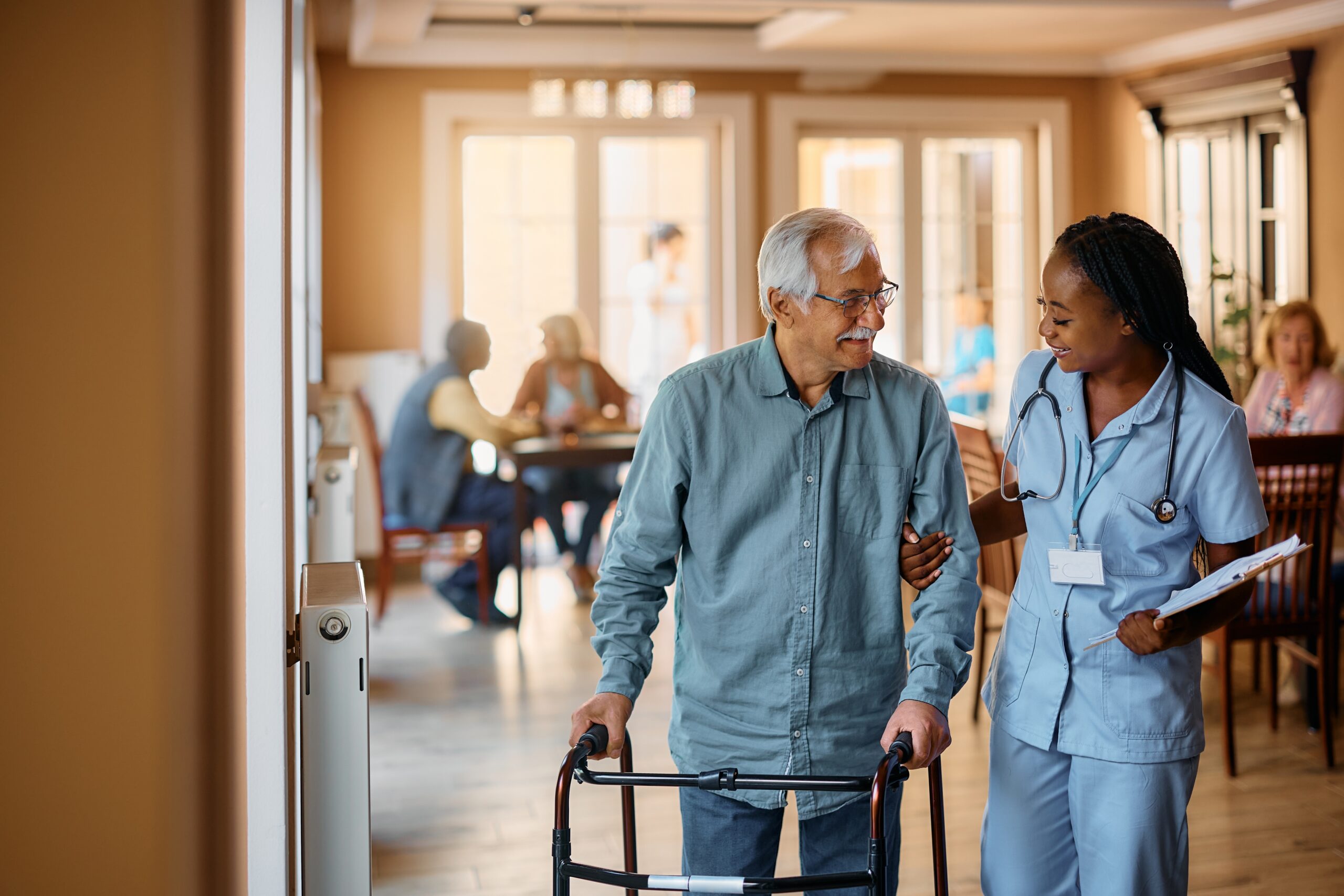 Happy,Senior,Man,Using,Mobility,Walker,While,African,American,Nurse